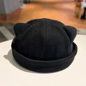 Detail of black docker hat featuring cute 3D cat ear accents and a thick rolled brim