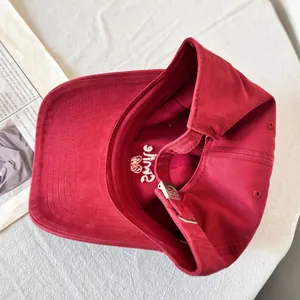 Close-up of red cotton baseball cap interior with white Smile embroidery and metal buckle