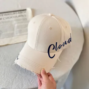Detalle de gorra beige con bordado Cloud azul y visera con acabado desgastado retro
