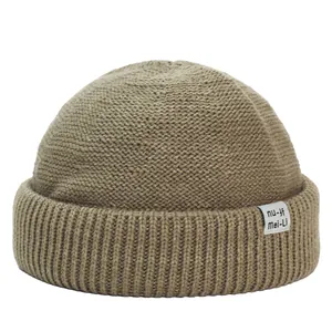 Dettaglio di un cappello in maglia a coste marrone chiaro con etichetta tessuta