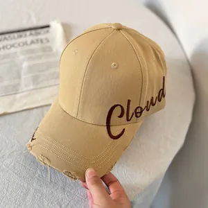 Detalle de gorra de béisbol caqui con bordado Cloud marrón y borde de visera desgastado