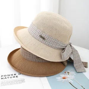 Summer woven straw bucket hats with ribbon bows in beige and camel colors for beach sun protection