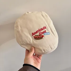 Dettaglio del ricamo American's Diner e grafica hot dog su berretto in tela beige