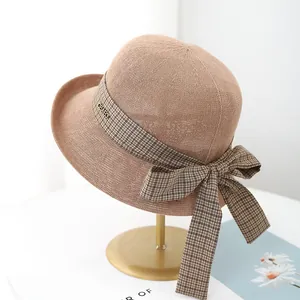 Women's summer straw sun hat with plaid ribbon bow and metallic brand tag detail