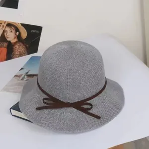 Detail of grey straw sun hat with woven texture and elegant brown bow ribbon