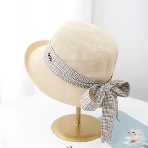 Close-up of summer straw hat with brown checkered ribbon and gold metal CBAFO buckle