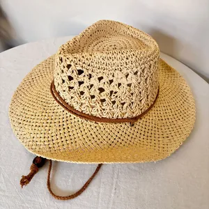 Détail d'un chapeau de paille tissé ajouré avec cordon décoratif et jugulaire réglable