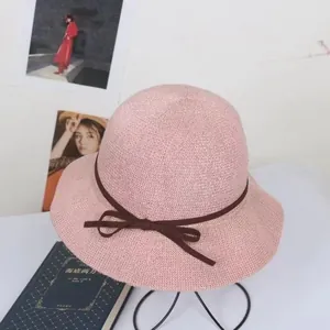 Detail of pink knitted sun hat with wavy brim and dark brown decorative bow ribbon