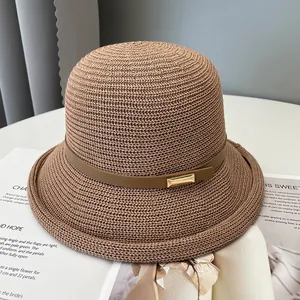 Dettaglio del cappello a secchiello in paglia marrone con cinturino in pelle e fibbia