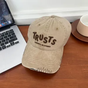 Macro shot of embroidered letters and distressed brim on a khaki cotton baseball cap