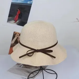 Detail of a beige woven sun hat with a brown ribbon bow on a stylish display stand