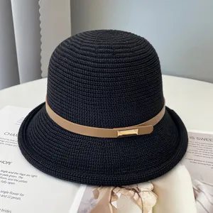 Dettaglio di cappello in paglia nera con cinturino in pelle kaki e fibbia dorata
