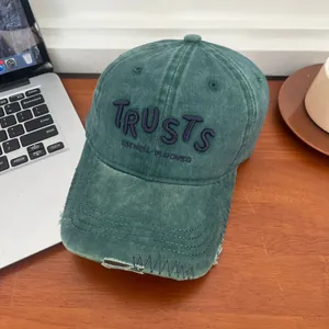 Close-up of distressed vintage dark green baseball cap with purple letter embroidery