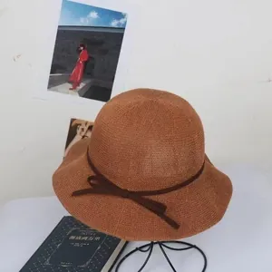 Detailed texture of brown woven straw hat with delicate bow and wavy brim design