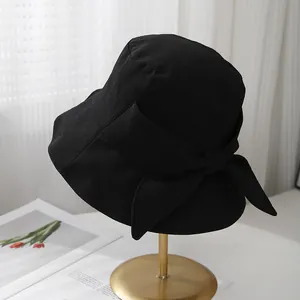 Détail d'un chapeau cloche noir avec grand nœud élégant sur un support doré