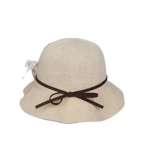 Elegant beige knit bucket hat for women with a dark brown bow and wavy brim design