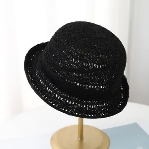 Chapeau cloche noir en maille ajourée pour femme présenté sur un support doré