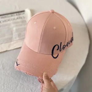 Detalle de gorra de algodón rosa con bordado Cloud azul y borde deshilachado de estilo retro