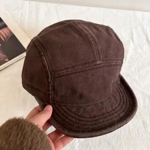 Close-up of deep brown five-panel baseball cap with detailed stitching and washed cotton texture