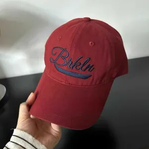 Detalle de gorra de béisbol granate con bordado Brkln azul marino en sarga de algodón
