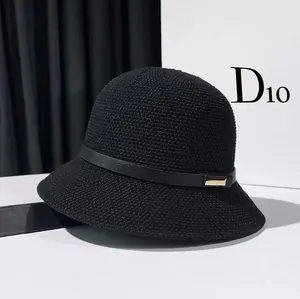 Close-up of black knitted bucket hat with fine texture and golden metal buckle detail