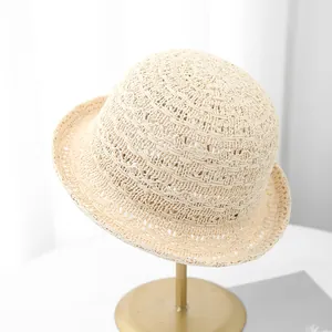 Détail d'un chapeau cloche en maille beige avec texture ajourée sur un support métallique