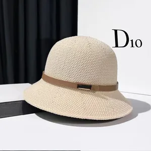 Close-up of beige woven bucket hat featuring a brown leather band and gold metal buckle