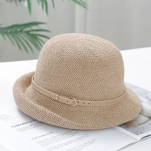 Detailed texture of beige woven straw sun hat with decorative slim leather belt buckle