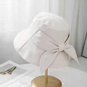 Détail du chapeau de soleil beige avec un grand nœud et une texture en sergé chic