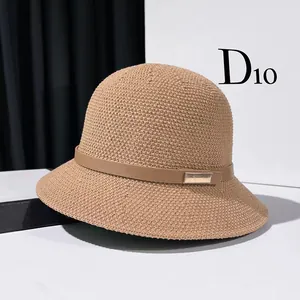 Detail of khaki knit bucket hat featuring a leather band and gold metal accent piece