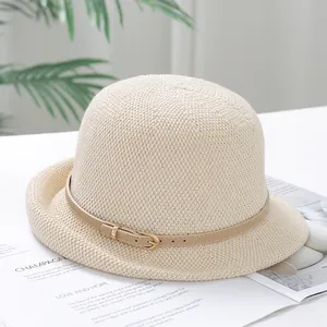 Close-up of beige knitted cloche hat with a leather belt buckle detail on a magazine