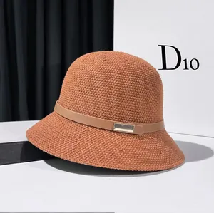 Detail of woven bucket hat in caramel brown with a leather strap and metallic buckle decoration