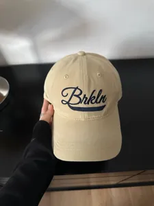Primer plano de gorra de béisbol de algodón beige con bordado cursivo Brkln en azul