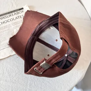 Detalle de gorra de béisbol vintage marrón oscuro con hebilla metálica y borde desgastado