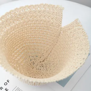 Detail of beige woven straw bucket hat featuring a rear split brim for hairstyles