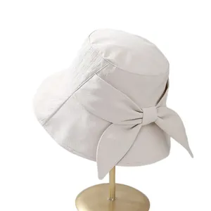 Chapeau de soleil ivoire élégant avec grand nœud sur support doré, style été chic