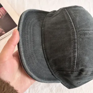 Close-up of a dark grey 5-panel washed cotton cap showing the fabric texture and stitching