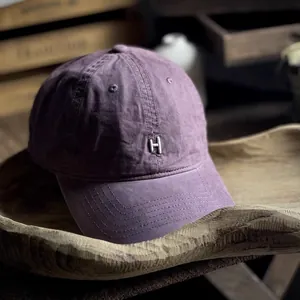Detailed view of silver metal H emblem on washed purple cotton vintage baseball cap