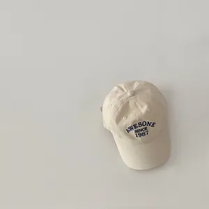 Close-up of vintage beige baseball cap featuring blue 'AWESOME SINCE 1987' embroidery