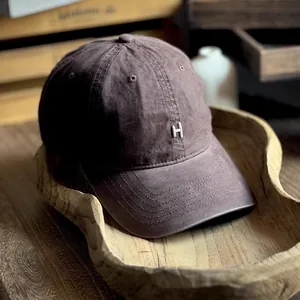 Vintage washed cotton baseball cap in deep brown with a metallic silver H logo