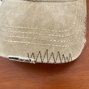 Detailed macro view of khaki washed cotton baseball cap with distressed stitching details