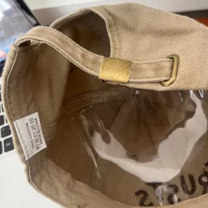 Close-up of cotton baseball cap with adjustable metal buckle and interior wash label