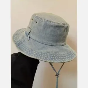 Detail of light blue washed denim bucket hat with metal eyelets and adjustable wind cord