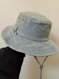 Close-up of light blue washed denim bucket hat with metal eyelets and adjustable chin cord