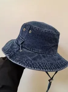 Detailed texture of washed denim bucket hat with metal eyelets and adjustable wind cord