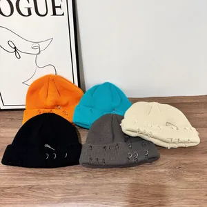Dettaglio di berretti in maglia in cinque colori con anelli di metallo e spille