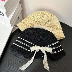 Detail of woven bucket hats with lace bows in beige and black on a wooden background