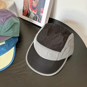 Detail of 5-panel camper hats featuring colorful ripstop fabric on a black wooden table