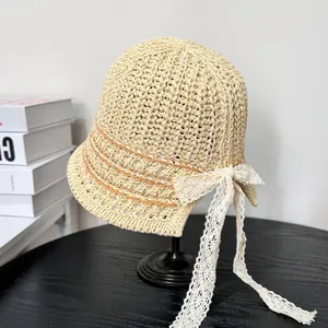 Close-up of hand-woven straw bucket hat with delicate lace bow and striped pattern