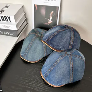 Vintage denim beret hats in three blue washes with contrast stitching on a wooden table
